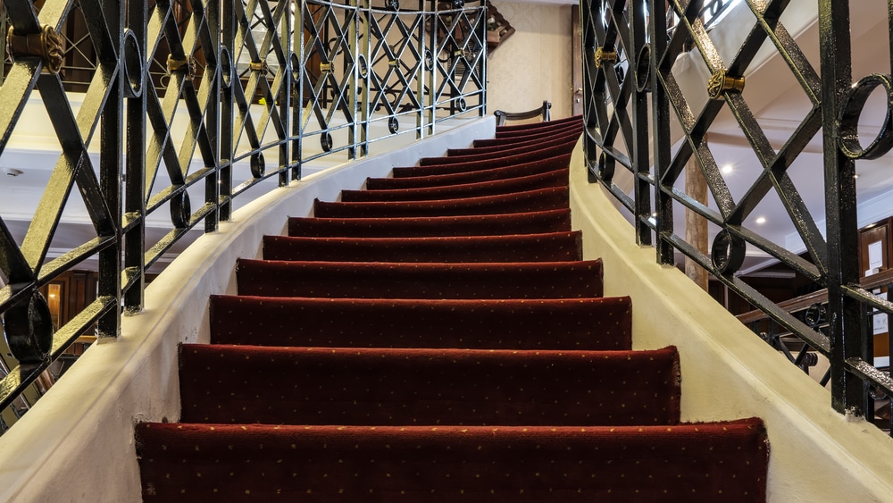 carpeted stairs with iron railings